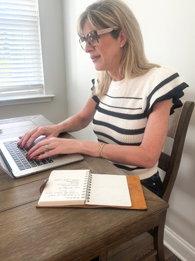 blonde woman sitting at desk working on laptop writing a blog post about managing change